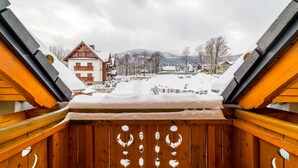 Een houten balkon met uitzicht op een besneeuwd dorp, inclusief gebouwen en bergen.