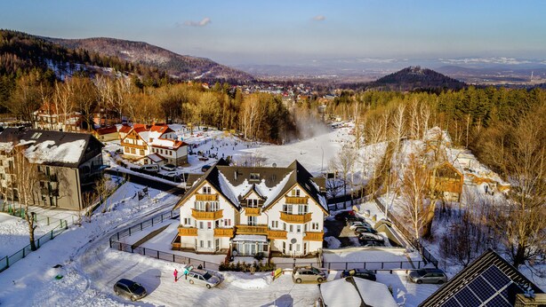 Een groot, meer verdiepingen tellend gebouw met een traditionele architectuur, omgeven door besneeuwde straten en een bergachtig landschap.