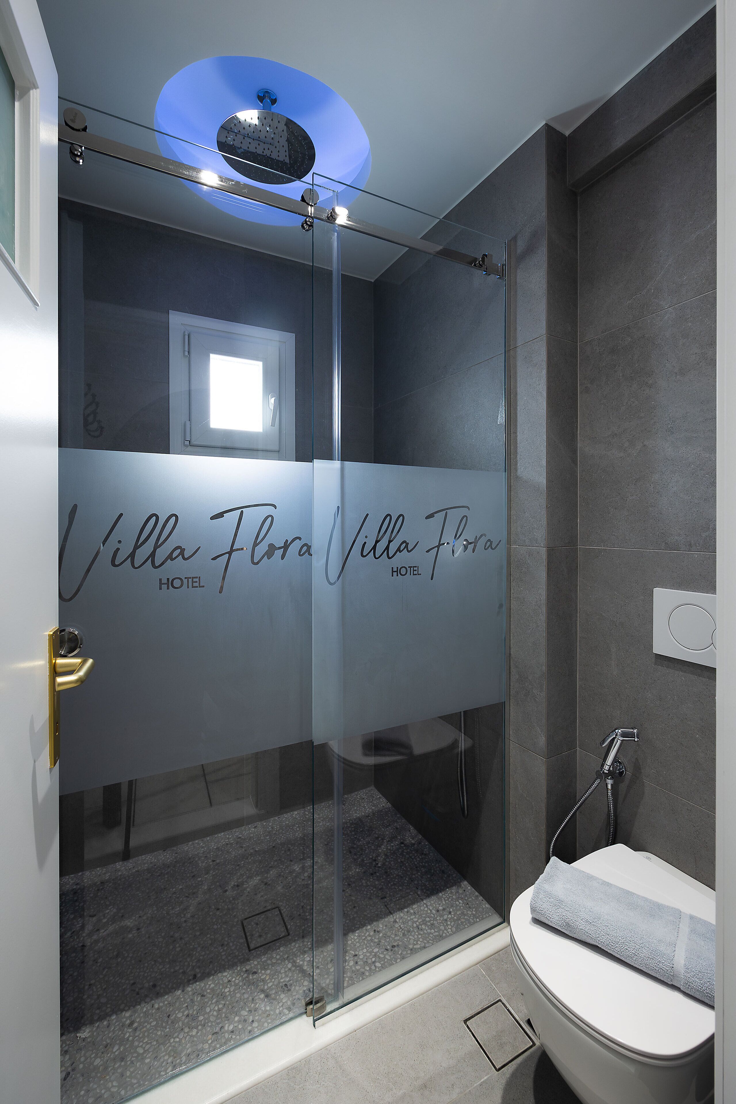 Ein modernes Badezimmer mit Duschkabine aus Glas, einer sichtbaren Toilette und einem Handtuchhalter.