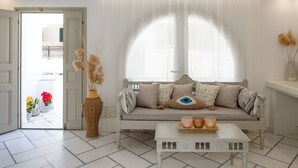Una sala de estar con sofá, una mesa de centro y una puerta que da a un balcón con flores.