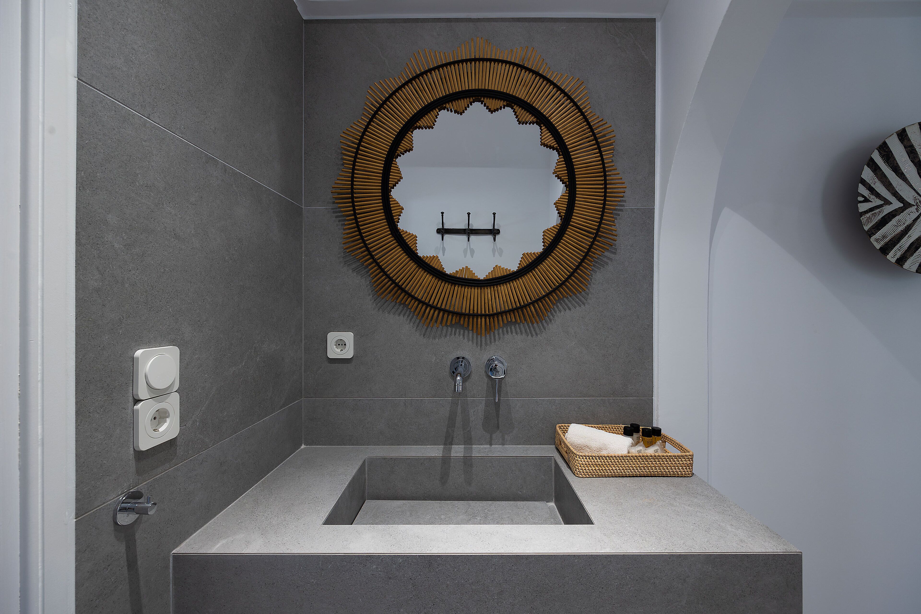 Un baño moderno con un espejo grande, un lavamanos rectangular y una pequeña cesta de mimbre sobre la encimera.