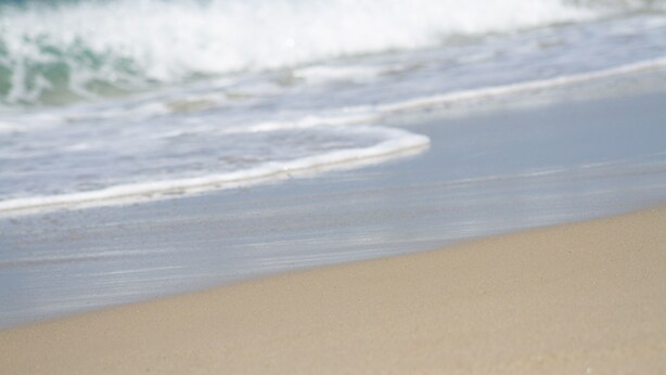 Una playa con olas acercándose a la orilla.