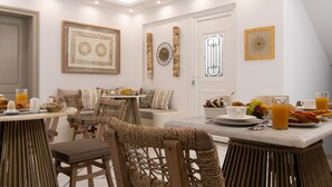 Un espacio para desayunar con una mesa, sillas y un sofá en una habitación luminosa con paredes y techo blancos.