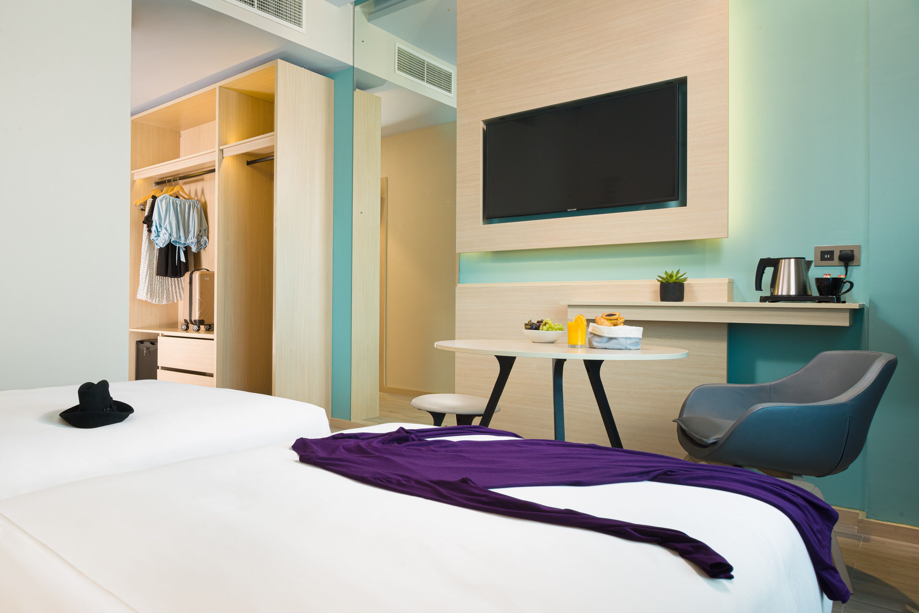 Una habitación de hotel con una cama, un escritorio, una silla, un televisor y un armario.
