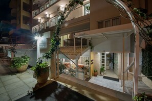 A multi-story hotel with a balcony on the upper floor, potted plants, and a staircase. - Lucky Suites (Rethymno)