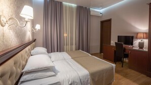 A hotel room with a bed, a desk, a chair, and an air conditioning unit. - Park Hotel Tskaltubo Balneo Resort (Tsqaltubo)