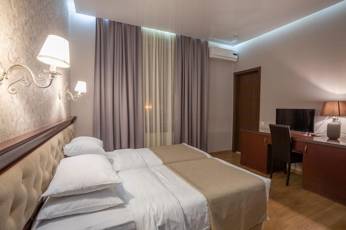 Una habitación de hotel con una cama, un escritorio, una silla y un equipo de aire acondicionado.