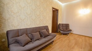 A living room with a brown sofa, a matching armchair, and patterned wallpaper. - Park Hotel Tskaltubo Balneo Resort (Tsqaltubo)