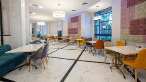 A spacious dining area with marble flooring, multiple tables and chairs, and large windows offering natural light. - Park Hotel Tskaltubo Balneo Resort (Tsqaltubo)