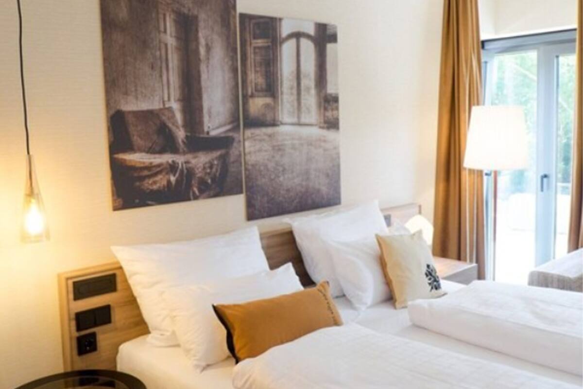 Una habitación de hotel con una cama grande, dos mesitas de noche y cuadros en la pared.