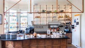 Una zona de bar con barra, estantes llenos de botellas y una máquina de café.