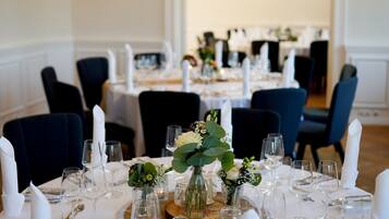 Una mesa de comedor formal cubierta con manteles blancos, copas y velas.