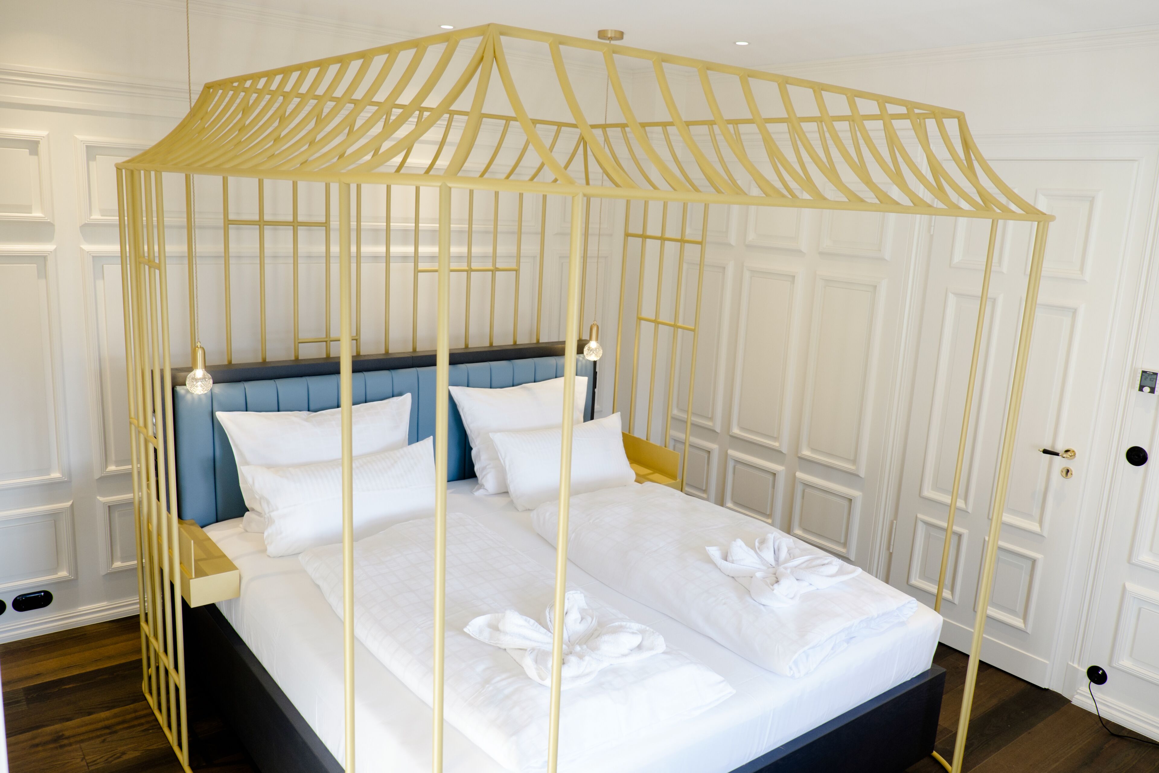 A bed with a canopy, white bedding, and a blue headboard.