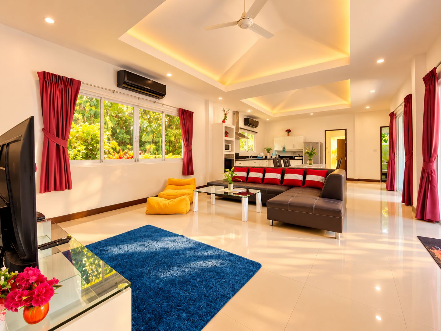 A spacious living area with a flat-screen TV, a sofa, a coffee table, and a blue rug.