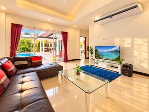 A modern living room with a leather sofa, a glass coffee table, and a flat-screen TV. - Private Pool Villa 4 bedrooms for family (Phuket)