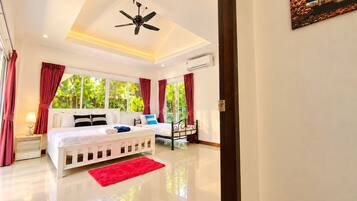 A hotel room with a bed, a red rug, a ceiling fan, and a window with curtains.