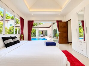 Un dormitorio con una cama grande, vistas a una piscina y un ventanal corredizo que da a un espacio exterior.