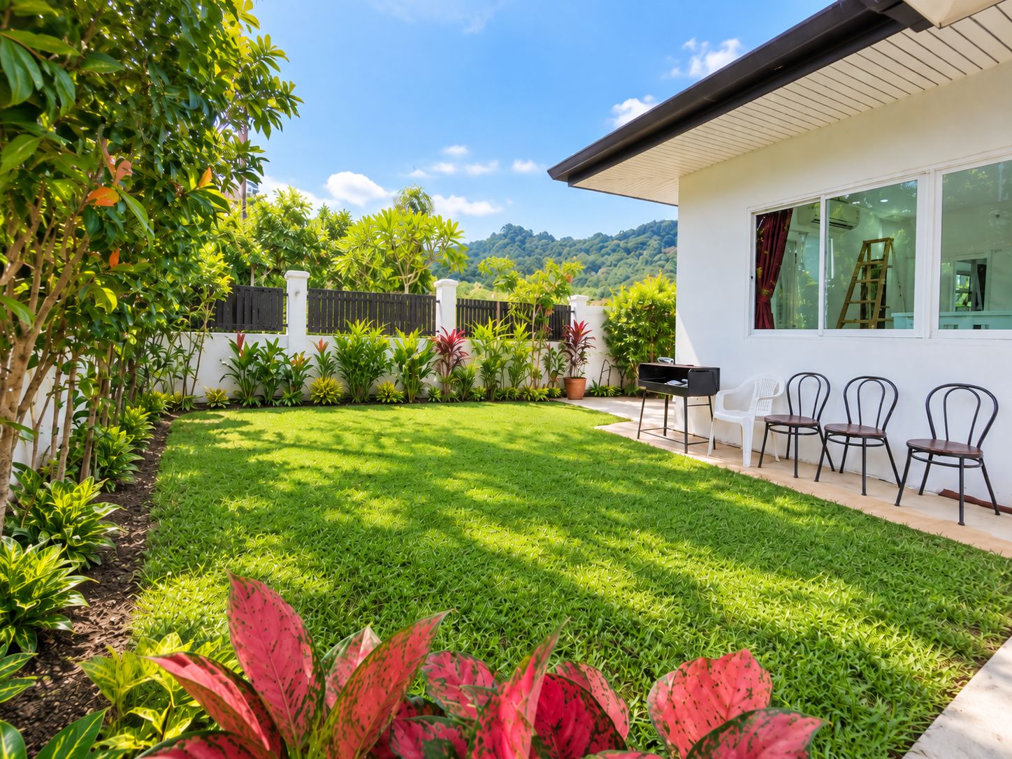 Una casa moderna con césped cuidado, zona de barbacoa y mobiliario de exterior.