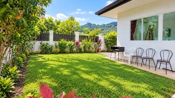 Una casa moderna con césped cuidado, zona de barbacoa y mobiliario de exterior.