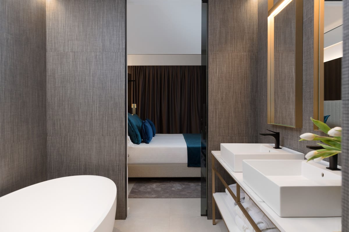 Un baño moderno con una bañera blanca grande, un lavabo doble y un espejo amplio.