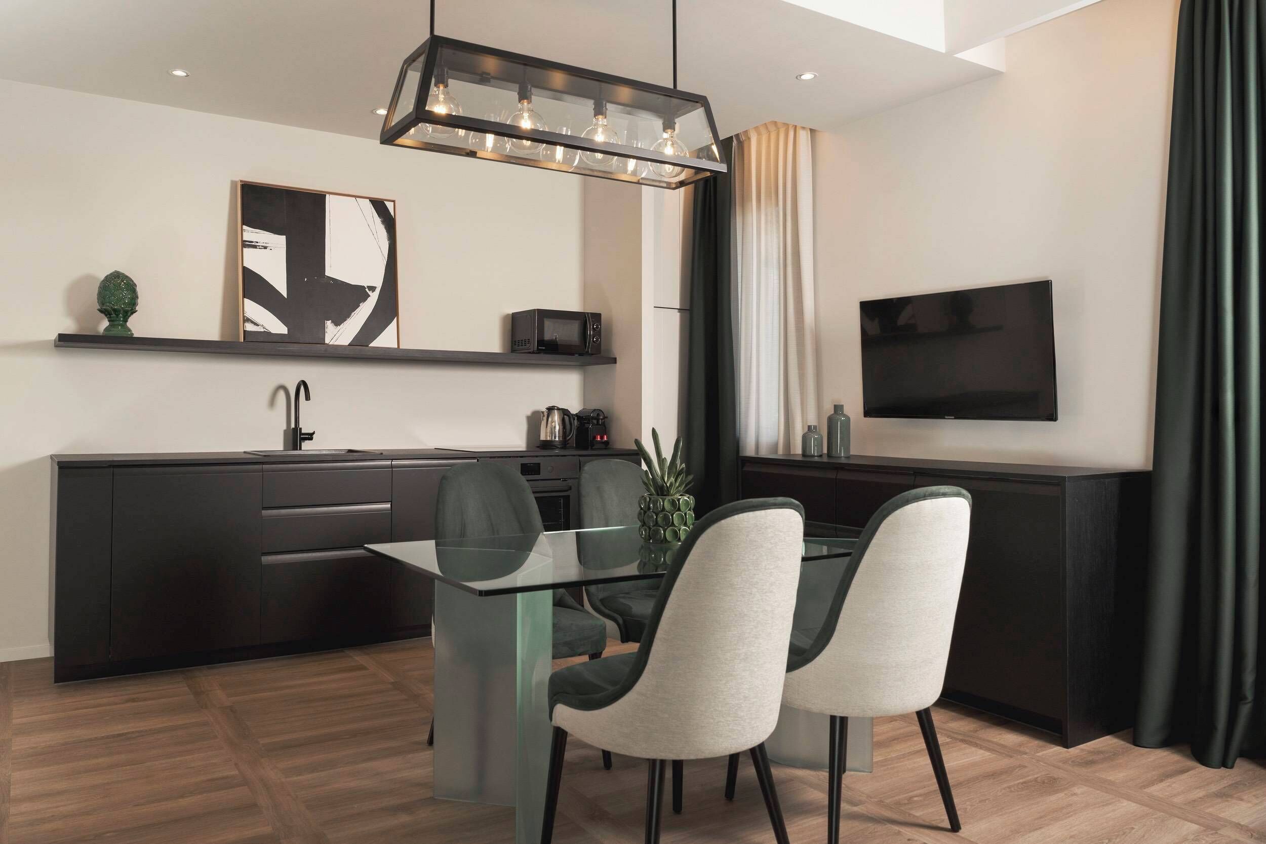 A modern kitchen with a dining area, a flat-screen TV, and a pendant light fixture.