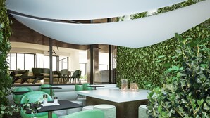 A modern indoor dining area with green chairs, a central table, and a wall covered in greenery. - We Me Suite Hotel (Riccione)