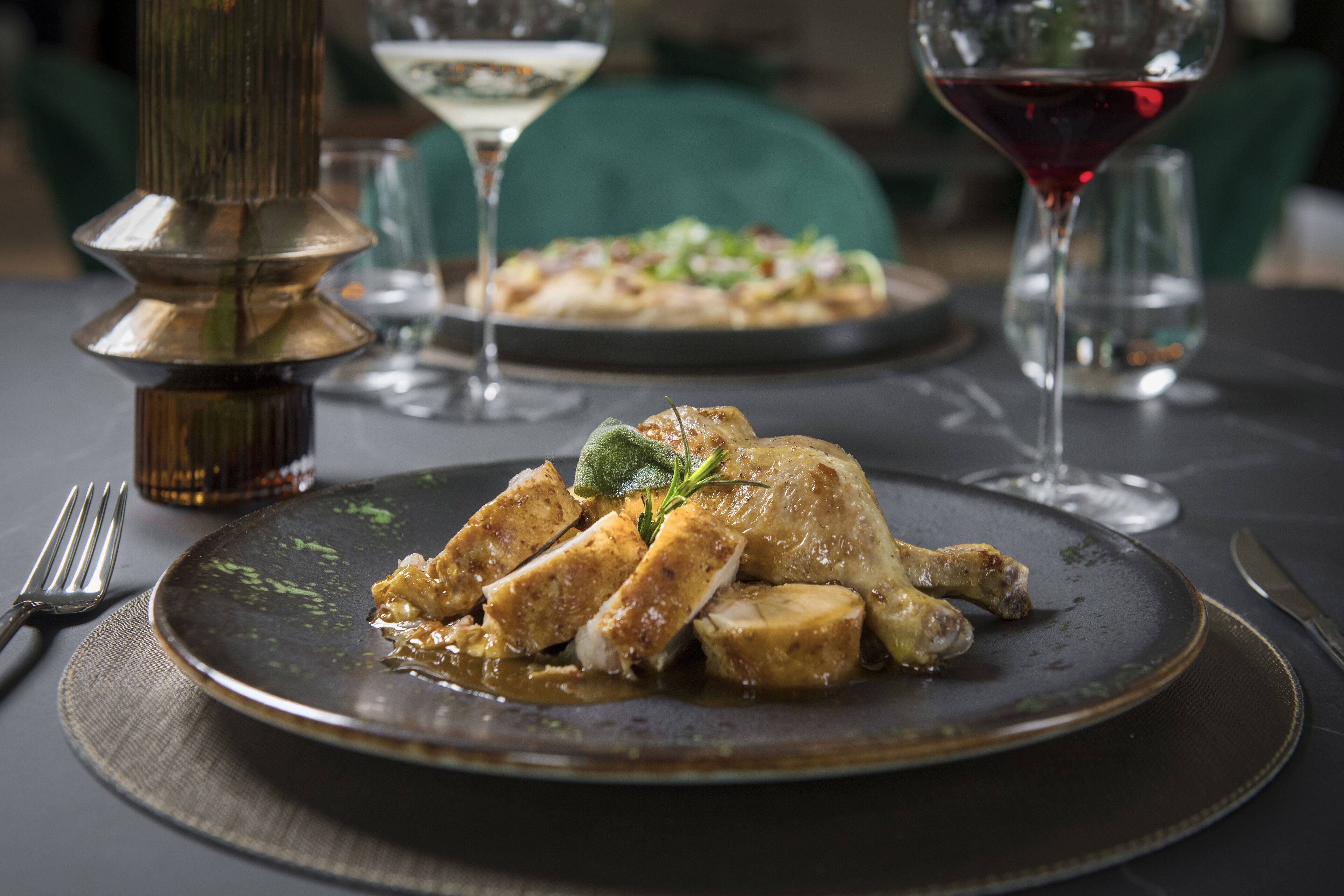 Une table à manger avec une assiette de nourriture, un verre à vin et une bougie.