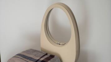 A round ottoman with a beige cushion and a plaid blanket draped over it.