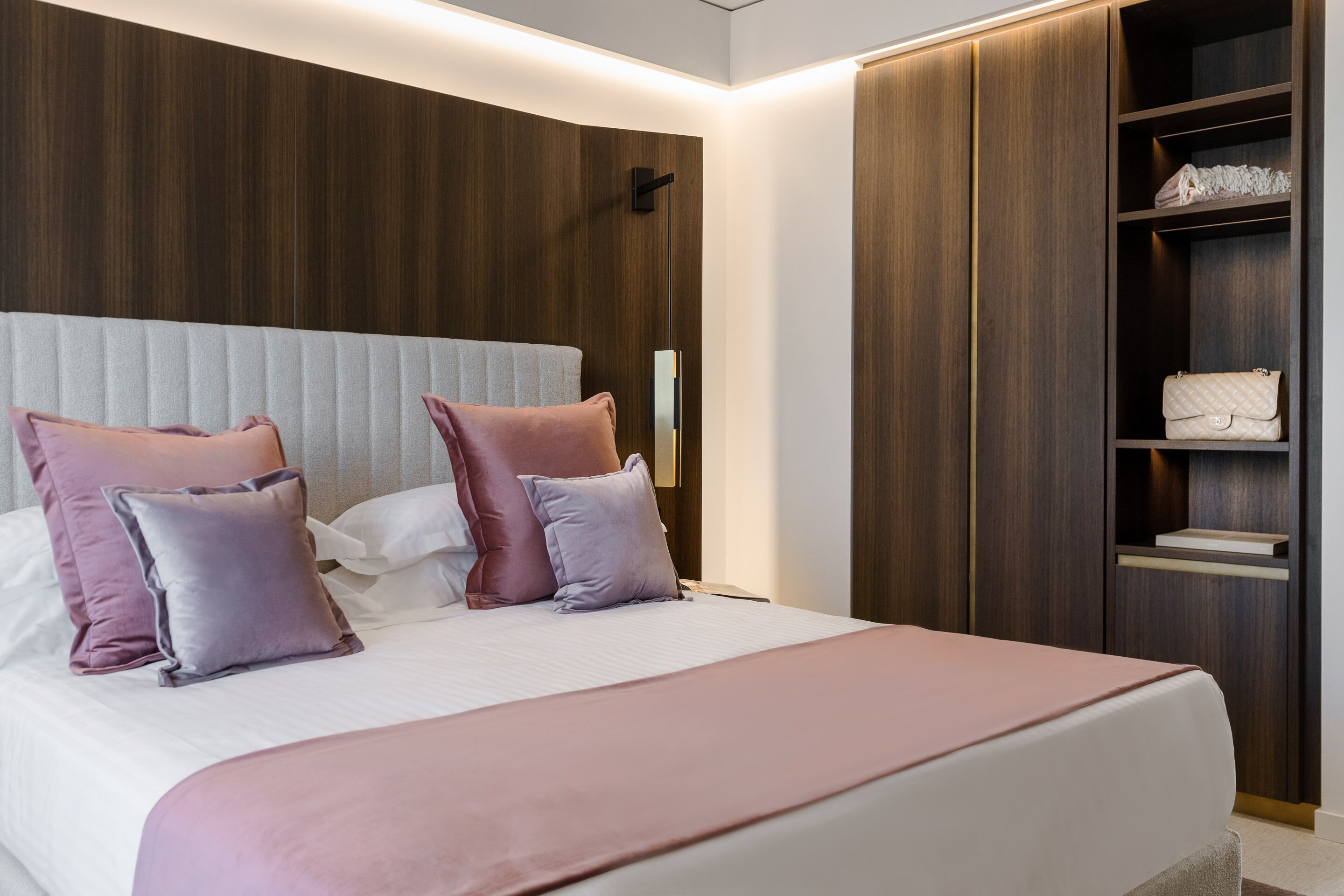 Un dormitorio moderno con una cama grande, cabecera de madera y armario empotrado.