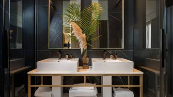 A modern bathroom with two sinks, a large mirror, and a decorative plant.