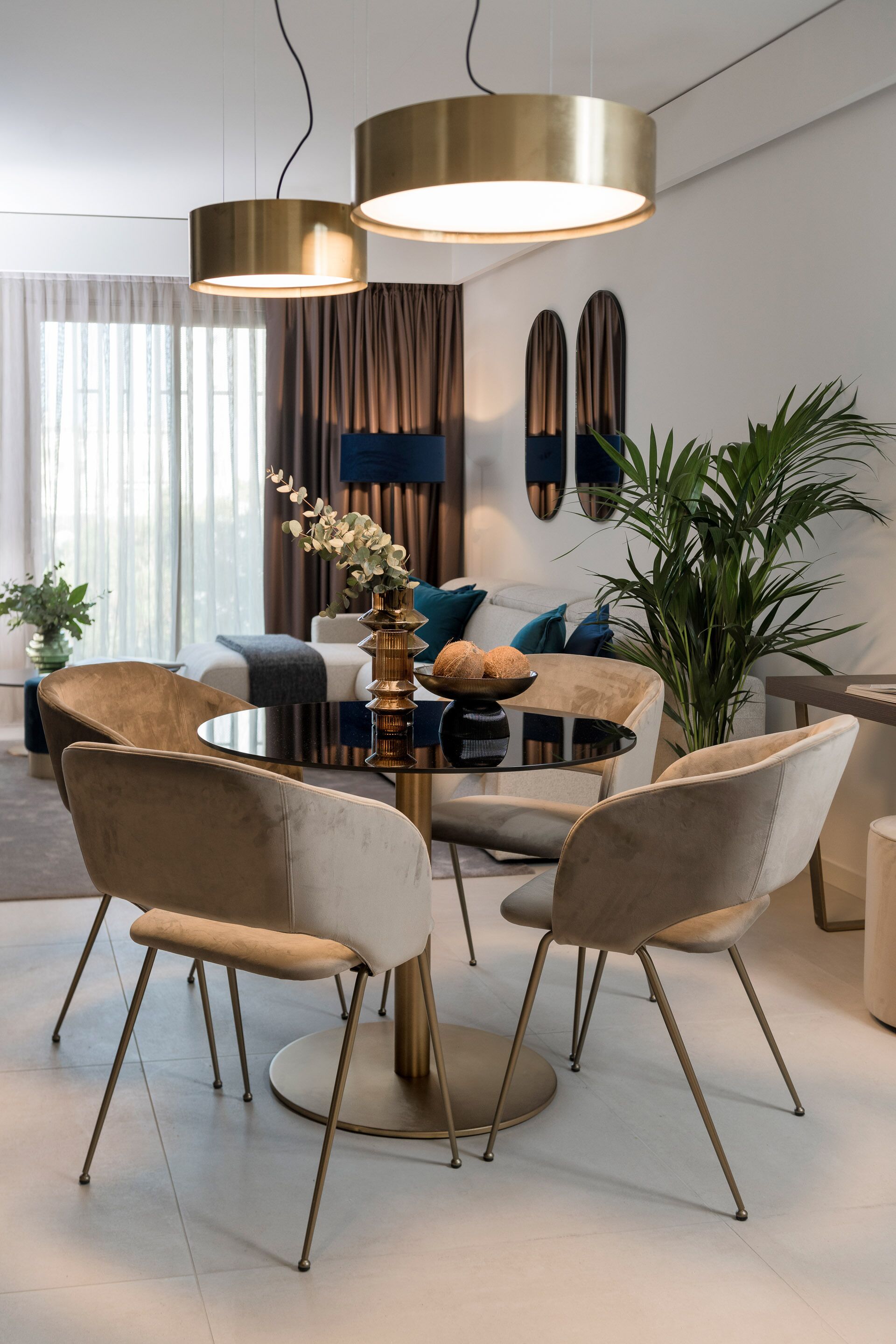 A modern dining area with a round table, four chairs, and two pendant lights.
