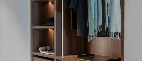 A modern closet with multiple shelves and hanging space, featuring a wooden finish and integrated lighting.
