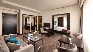 Une chambre d’hôtel équipée d’un canapé, d’un bureau, d’un lit, d’une télévision et d’un miroir.