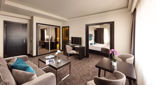 A hotel room with a sofa, a desk, a bed, a TV, and a mirror. - Old Town Hotel (Timisoara)