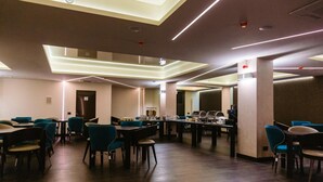 Un espace repas moderne avec des tables et des chaises, un comptoir où sont présentés des aliments, et un plafond doté d’un éclairage encastré.