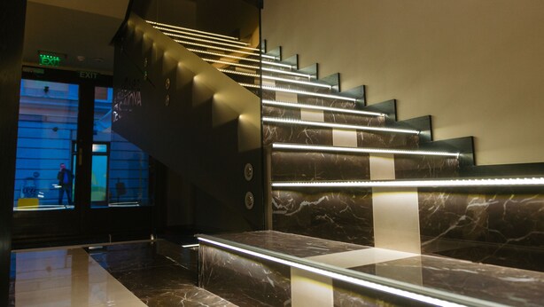 Un escalier moderne avec des rampes en verre et un éclairage à DEL.
