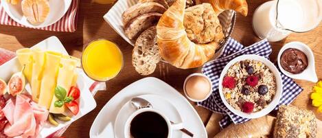 A breakfast spread with croissants, pastries, cheese, and fruit.