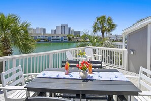 A deck with a table, chairs, and a view of a body of water and buildings.