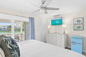 Quarto com cama, ventoinha no teto, televisão, cómoda e frigorífico.