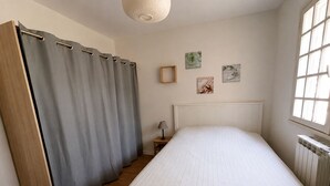 Une chambre à coucher avec un lit, une table de chevet, une fenêtre et un radiateur.