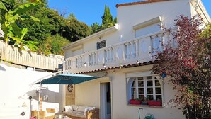 A white building with a balcony, wicker furniture, and potted plants. - Quiet house near Nice (Contes)