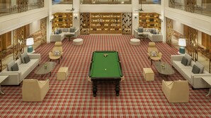 Um hall amplo com mesa de bilhar, áreas de estar e uma grande estante.