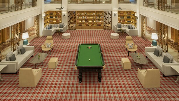 Um hall amplo com mesa de bilhar, áreas de estar e uma grande estante.