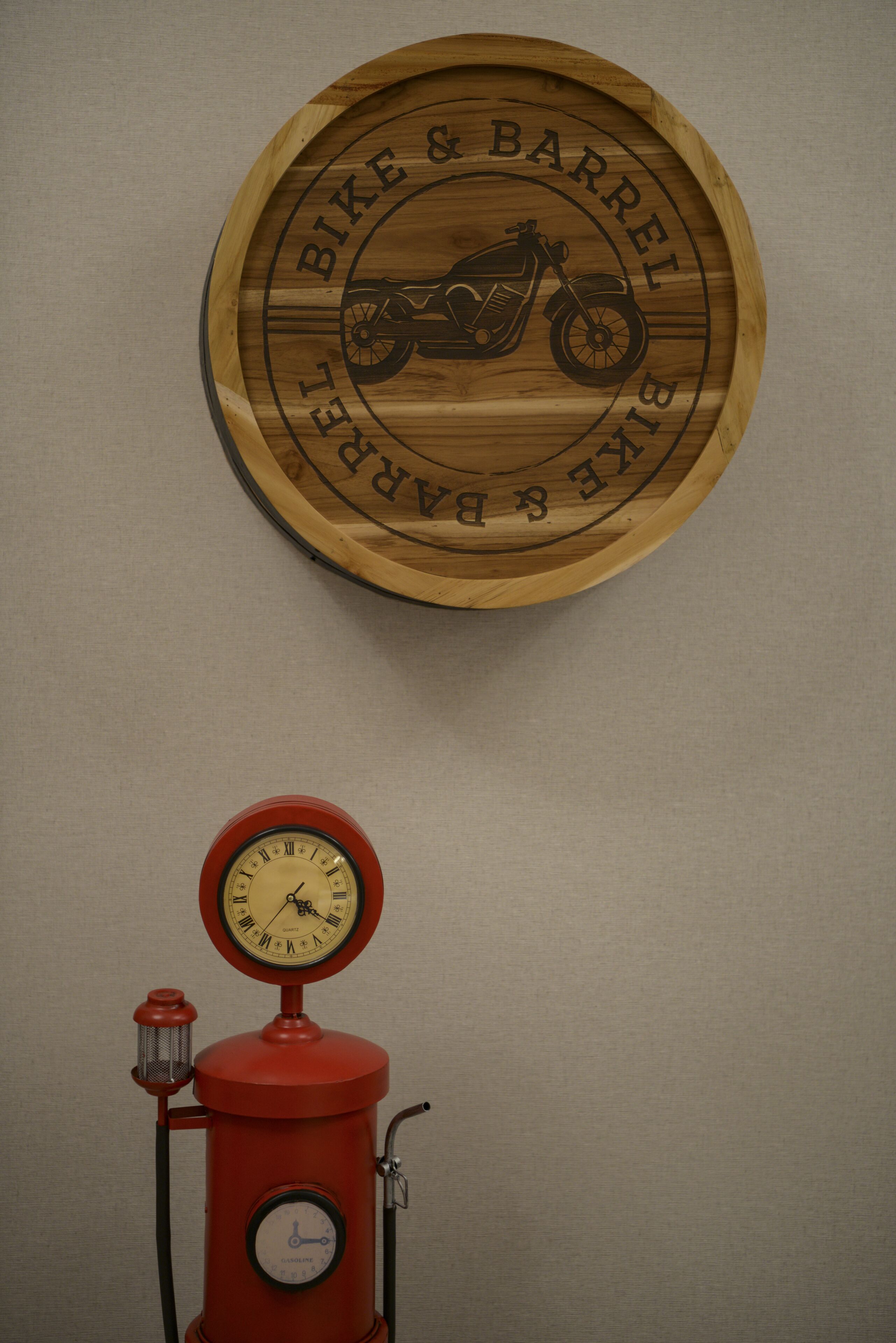 A wooden sign with a motorcycle and text, and a red gas pump with a clock below it.