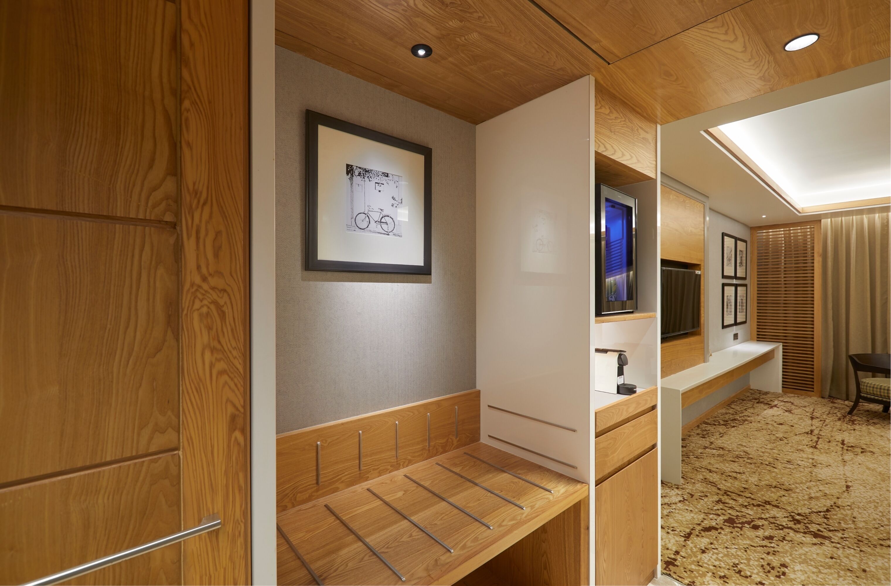 A modern bathroom with wooden cabinetry, a framed artwork, a mirror, and a shower area.