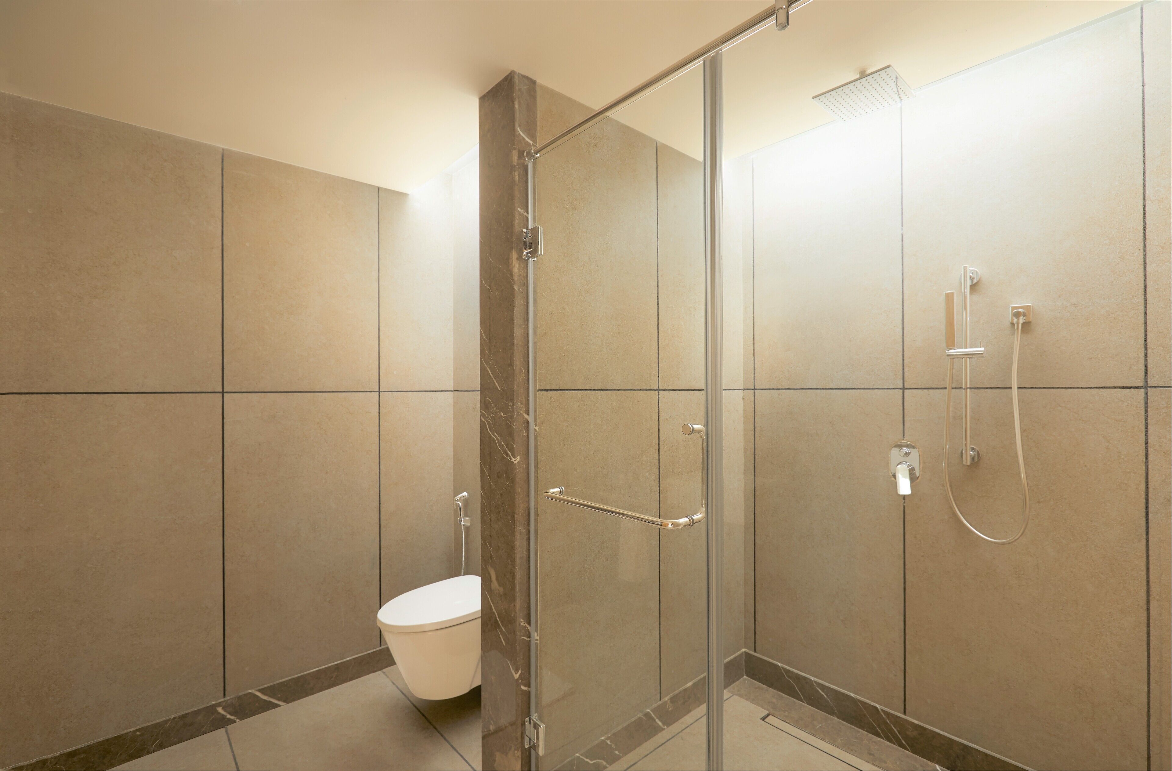 A modern bathroom with a glass-enclosed shower, a toilet, and a marble-tiled wall.