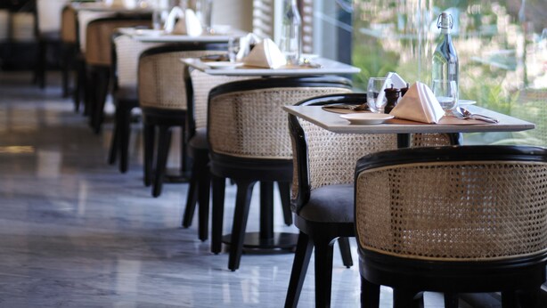 A restaurant interior with multiple tables and chairs, pendant lighting, and a view of greenery outside. - The Residency Towers Puducherry (Puducherry)