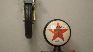 A vintage motorcycle and a Shell gas pump against a wall.