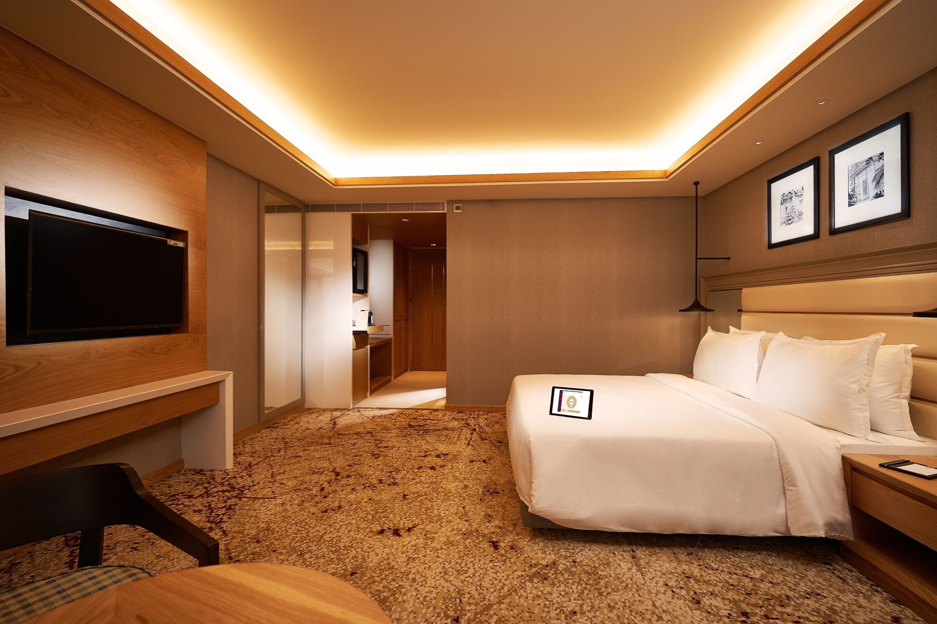 Una habitación de hotel con cama, mesita de noche, televisor y piso alfombrado.