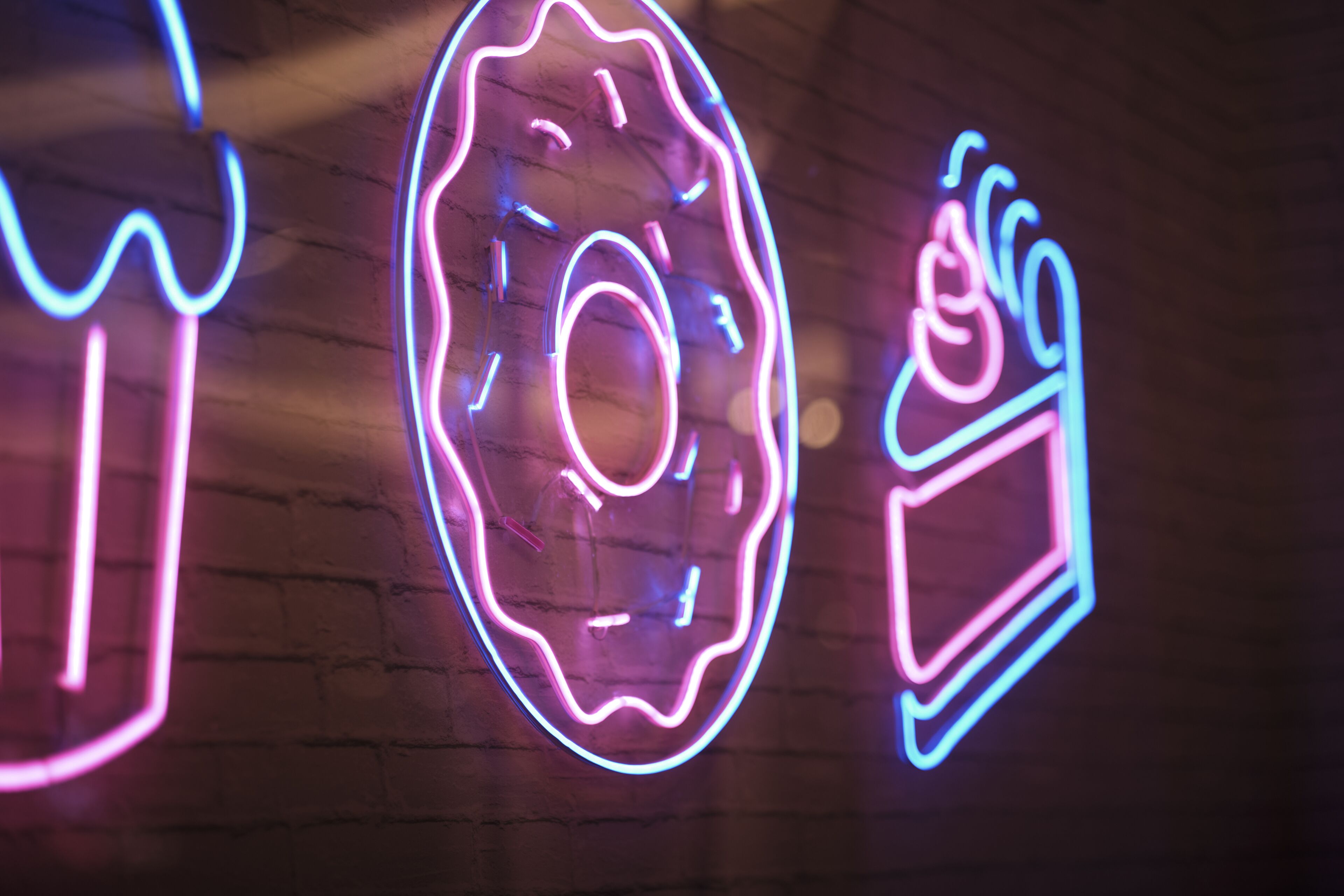 A neon sign with a donut and a coffee cup design.